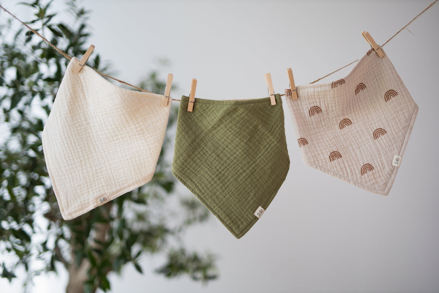 SOALSA baby bibs hanging on a clothesline with neutral colors and patterns rutice za dojenčke