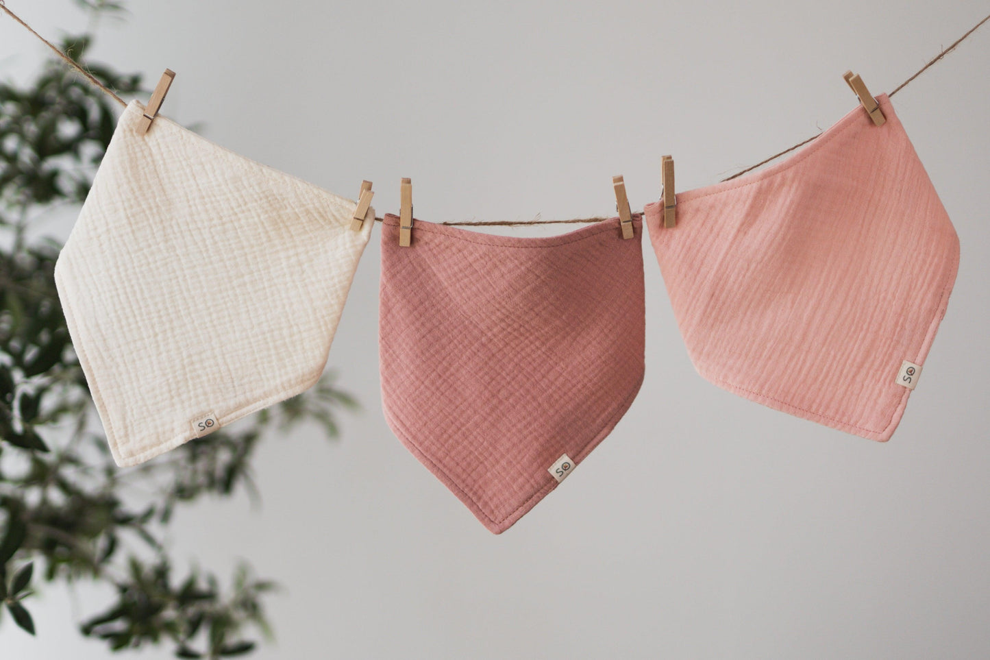 SOALSA baby bibs in cream, dusty rose, and soft pink hanging on a clothesline rutice za dojenčke