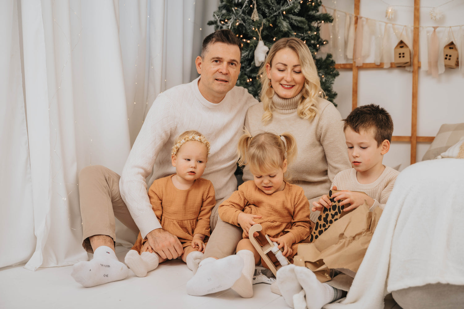 Happy family with children wearing Božična oblačila za otroke relaxing by decorated Christmas tree
