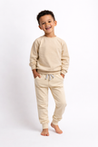 Child wearing a beige sweatshirt and pants set on a white background