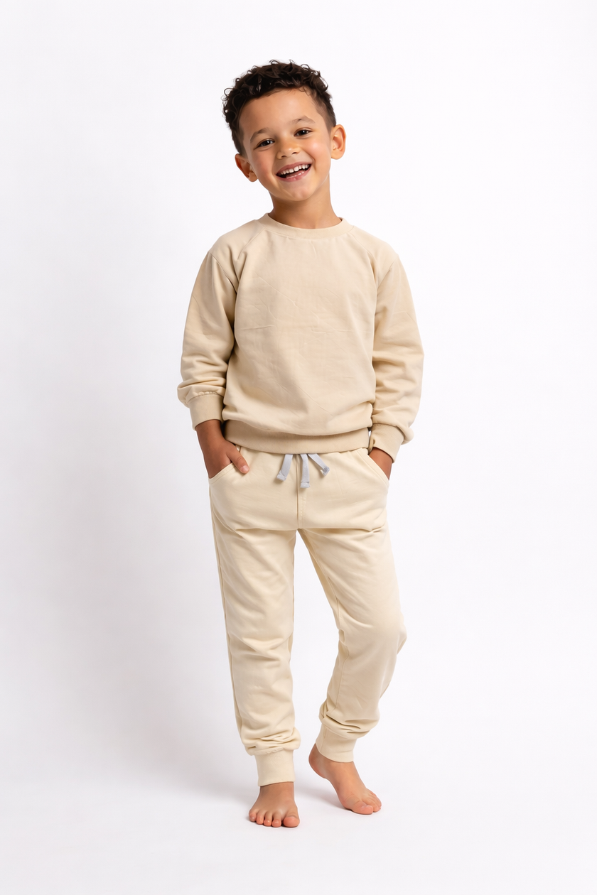 Child wearing a beige sweatshirt and pants set on a white background