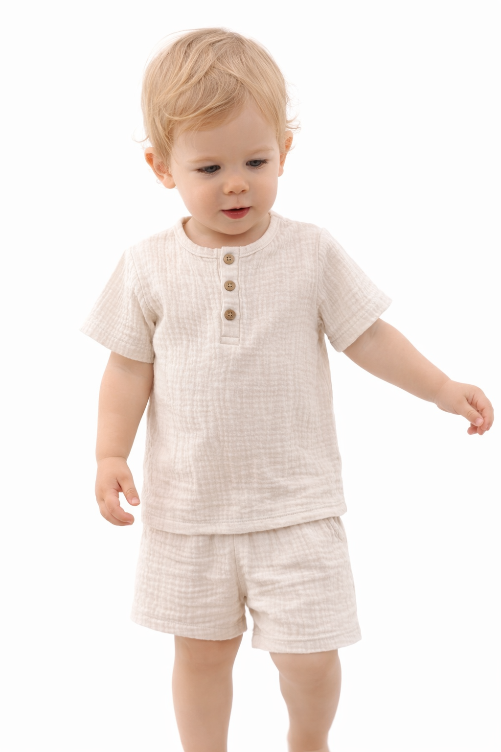 Child wearing a beige outfit with buttons on a white background