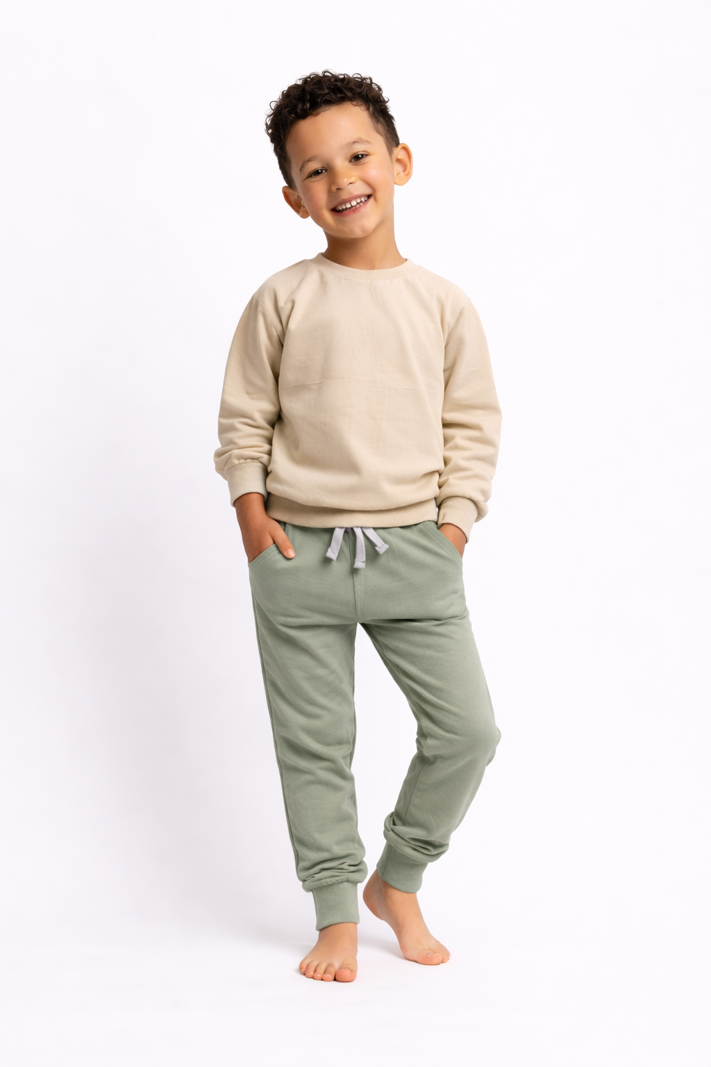 Child wearing a beige sweatshirt and green pants on a white background