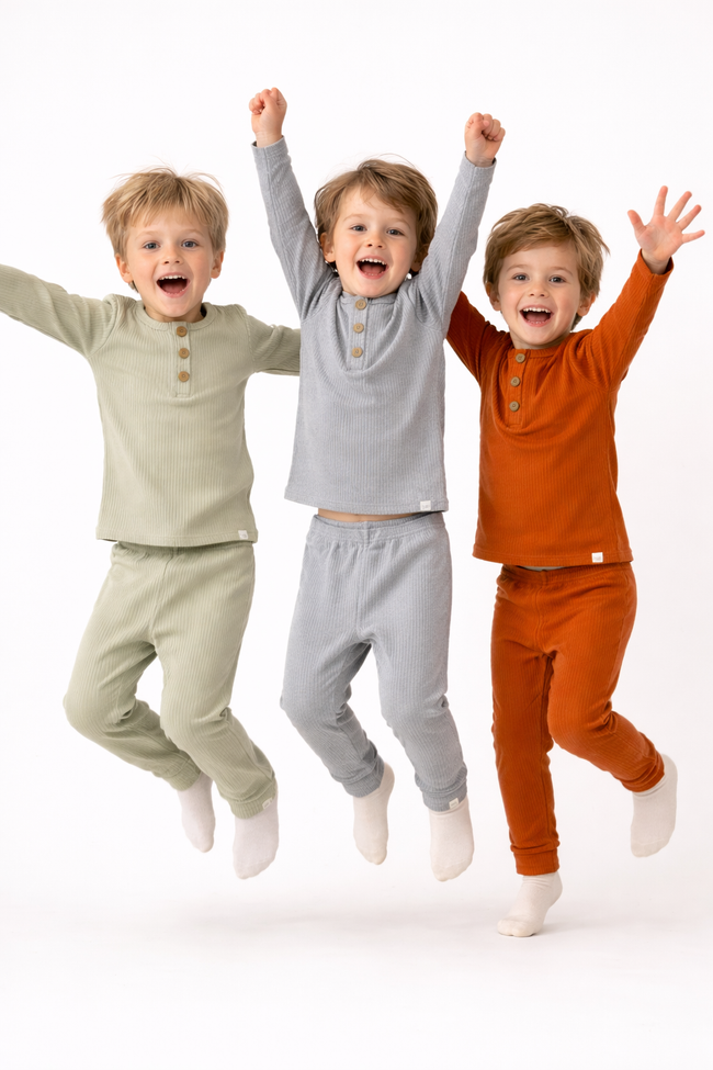 Three children in colorful outfits jumping against a white background
