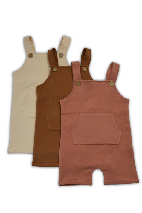 Three children's overalls in beige, brown, and pink on a white background