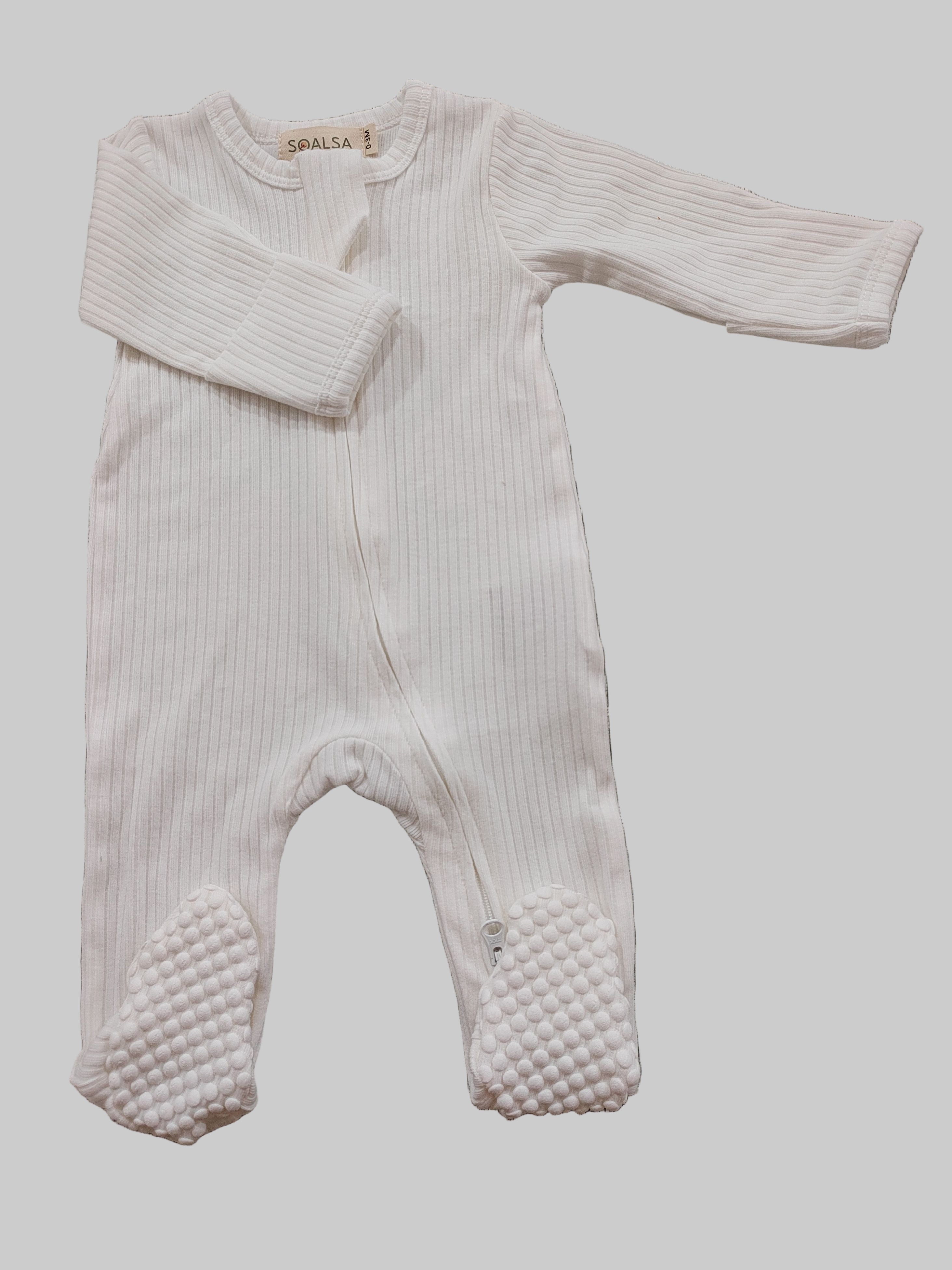 Baby onesie with textured feet on a gray surface