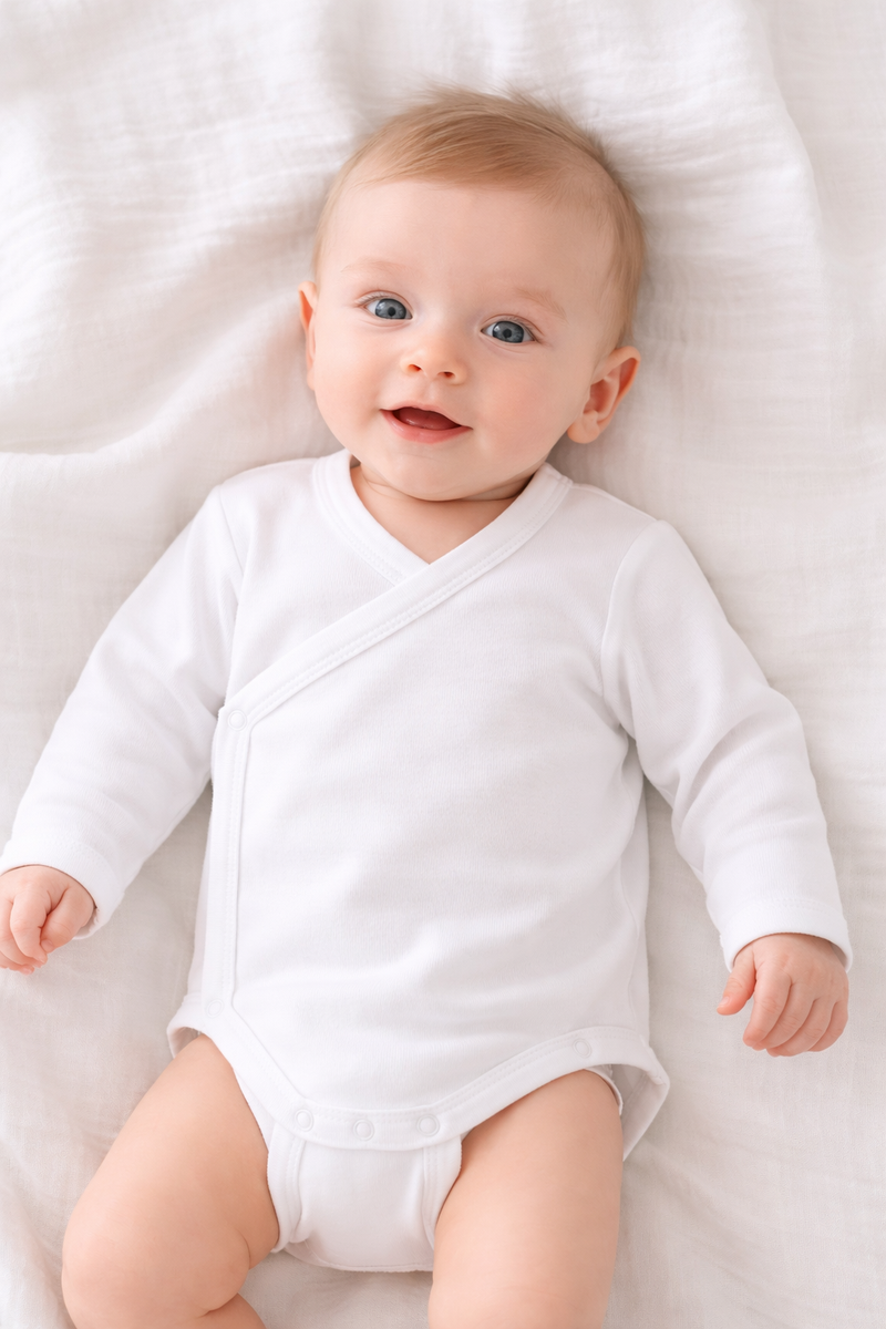 Baby wearing a white onesie lying on a white blanket