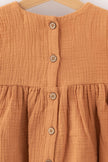 Close-up of brown textured fabric dress with wooden buttons by SOALSA Božična obleka za deklice