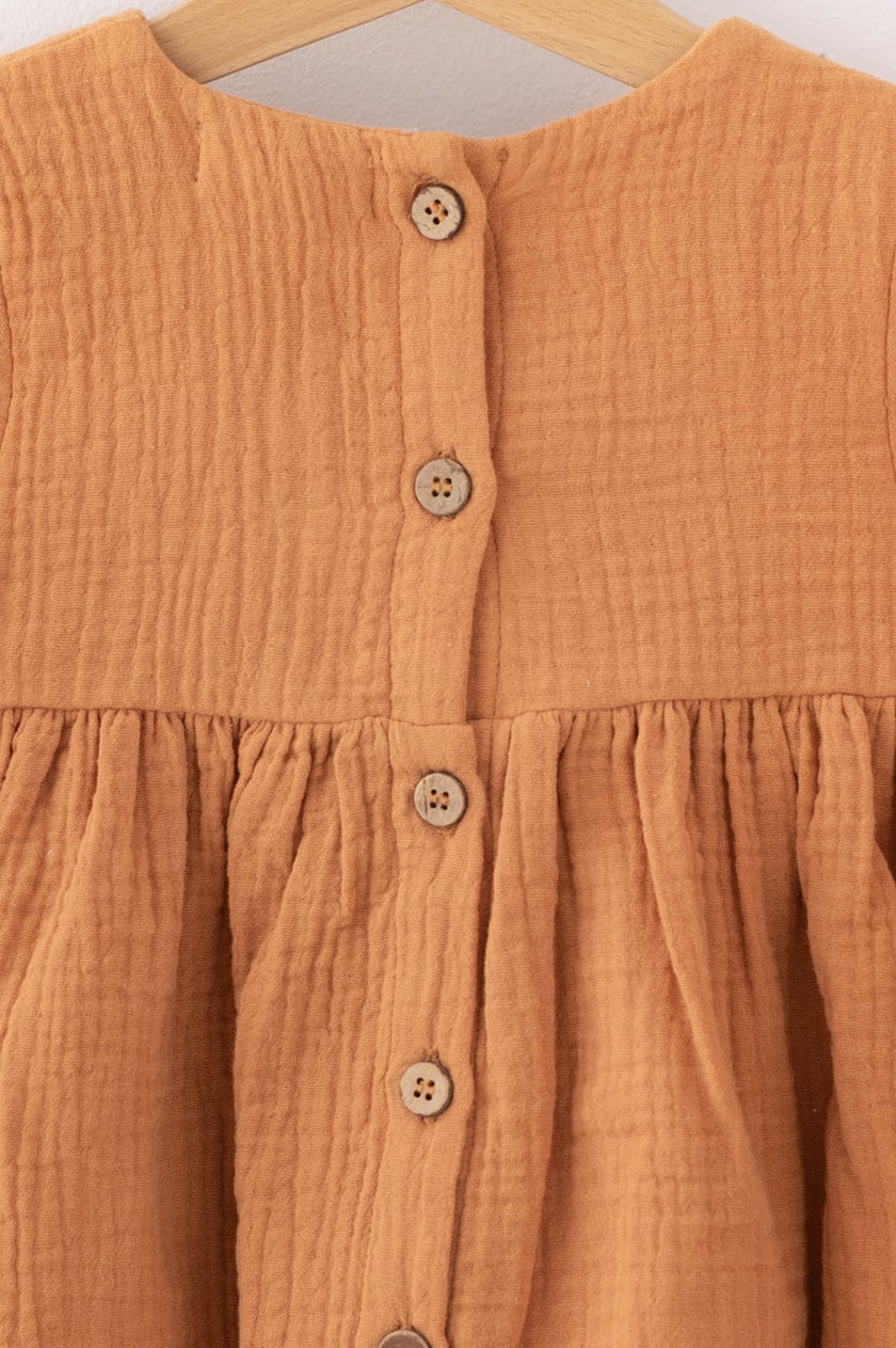 Close-up of brown textured fabric dress with wooden buttons by SOALSA Božična obleka za deklice