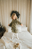 Child wearing SOALSA muslin dress in cozy room with Christmas decorations Božične obleke za otroke