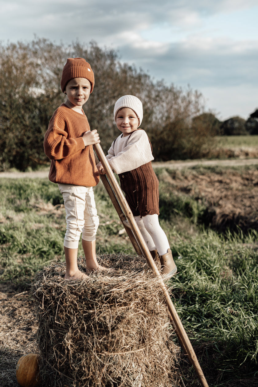 Two children outdoors wearing cozy božični puloverji za otroke by SOALSA during fall