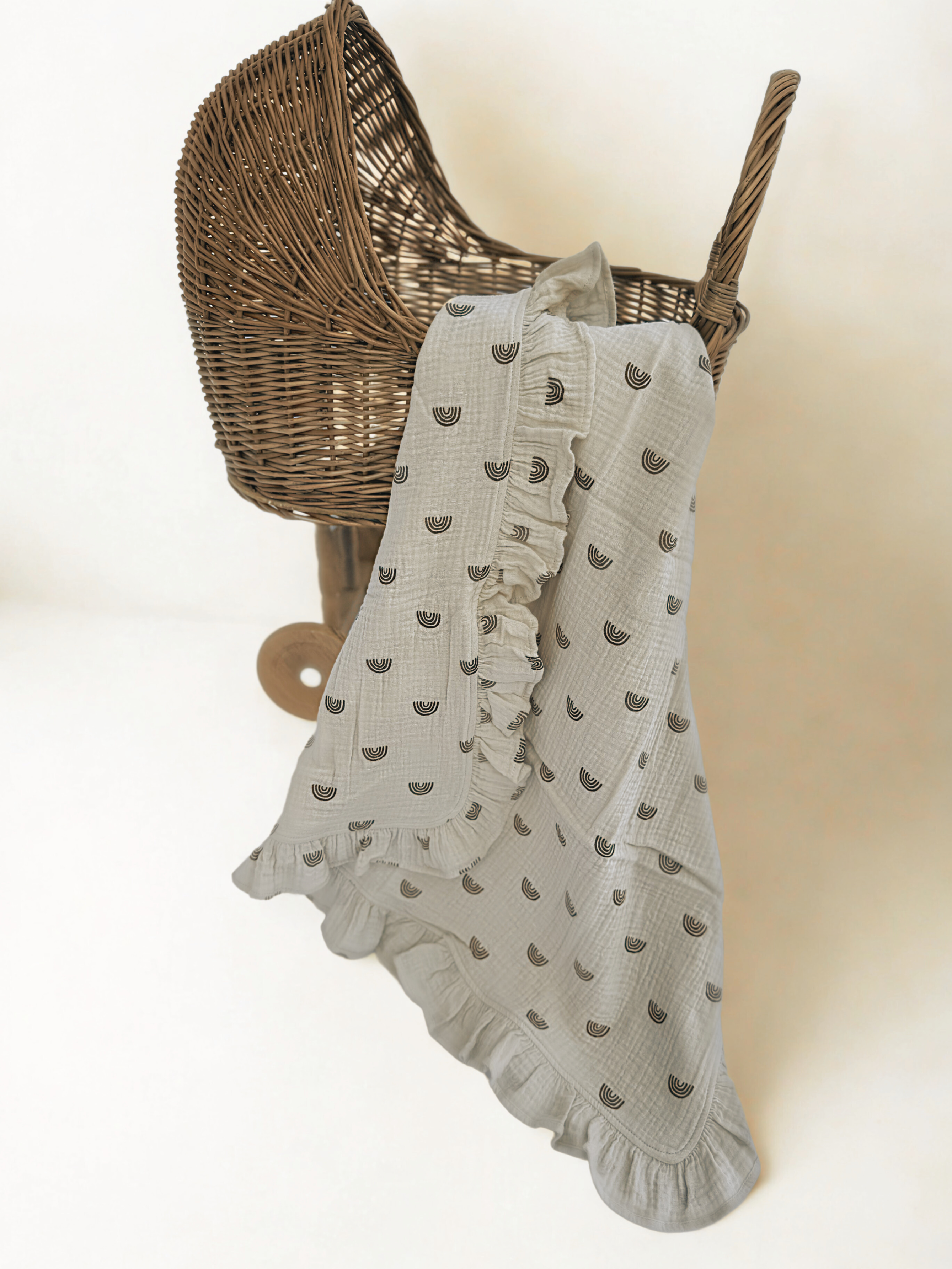 SOALSA gift set featuring a soft baby blanket with ruffled edges draped over a wicker bassinet Darilo za novorojenčka