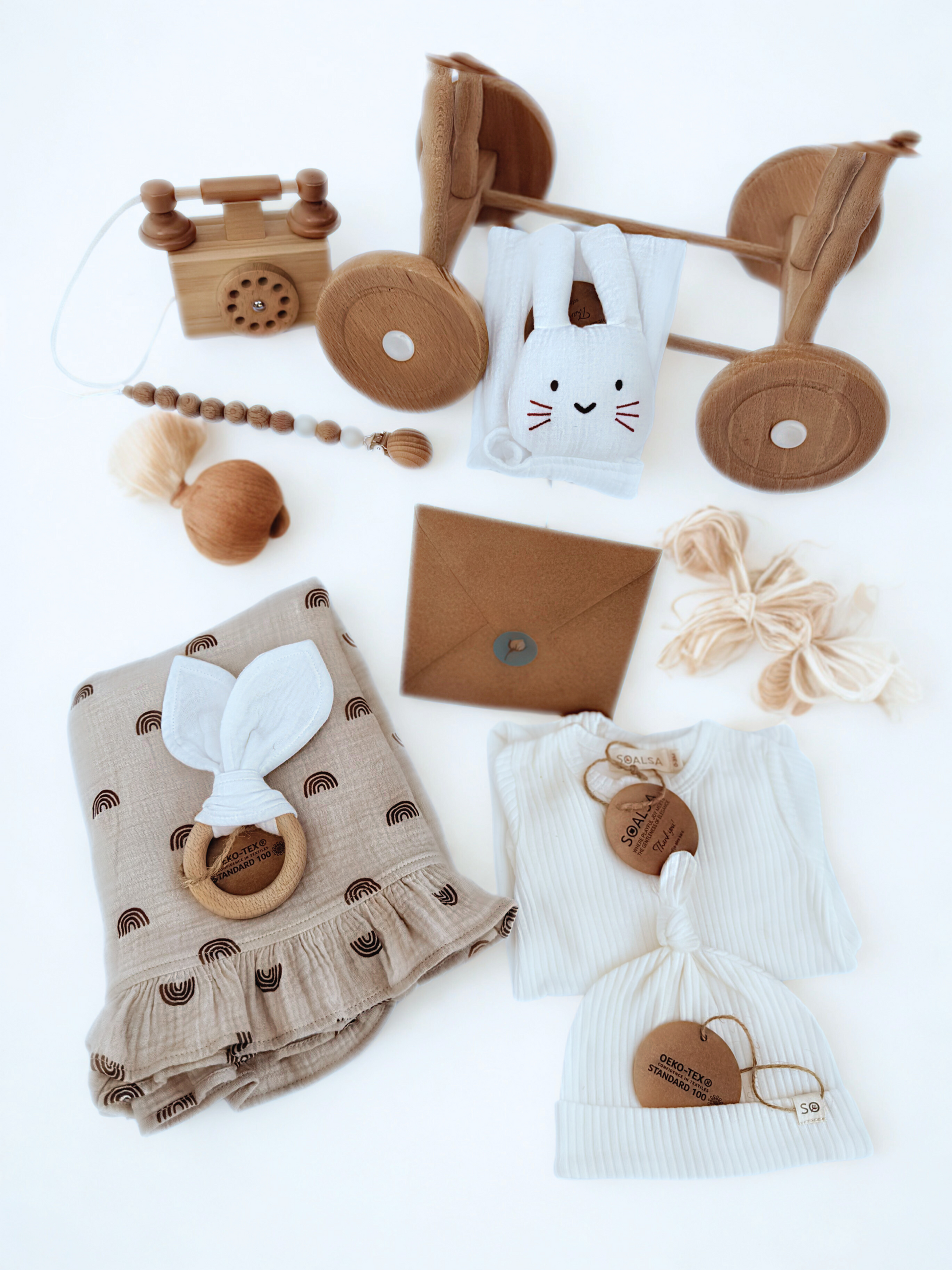 SOALSA Darilo za novorojenčka gift set with wooden toys, soft fabric items, and knitted baby accessories