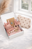 Baby gift set with plush toy, teether, and blanket in a box on a light surface.