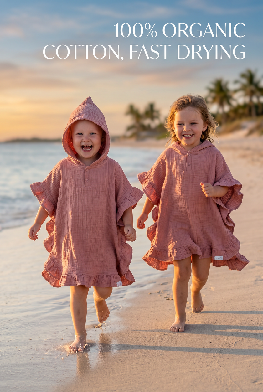 Two children wearing pink hooded towels on a beach with text about organic cotton and fast drying.