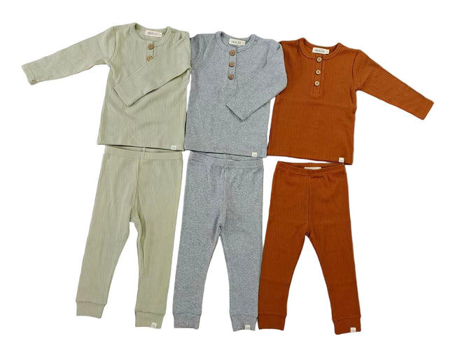 Three sets of children's pajamas in green, gray, and orange on a gray background