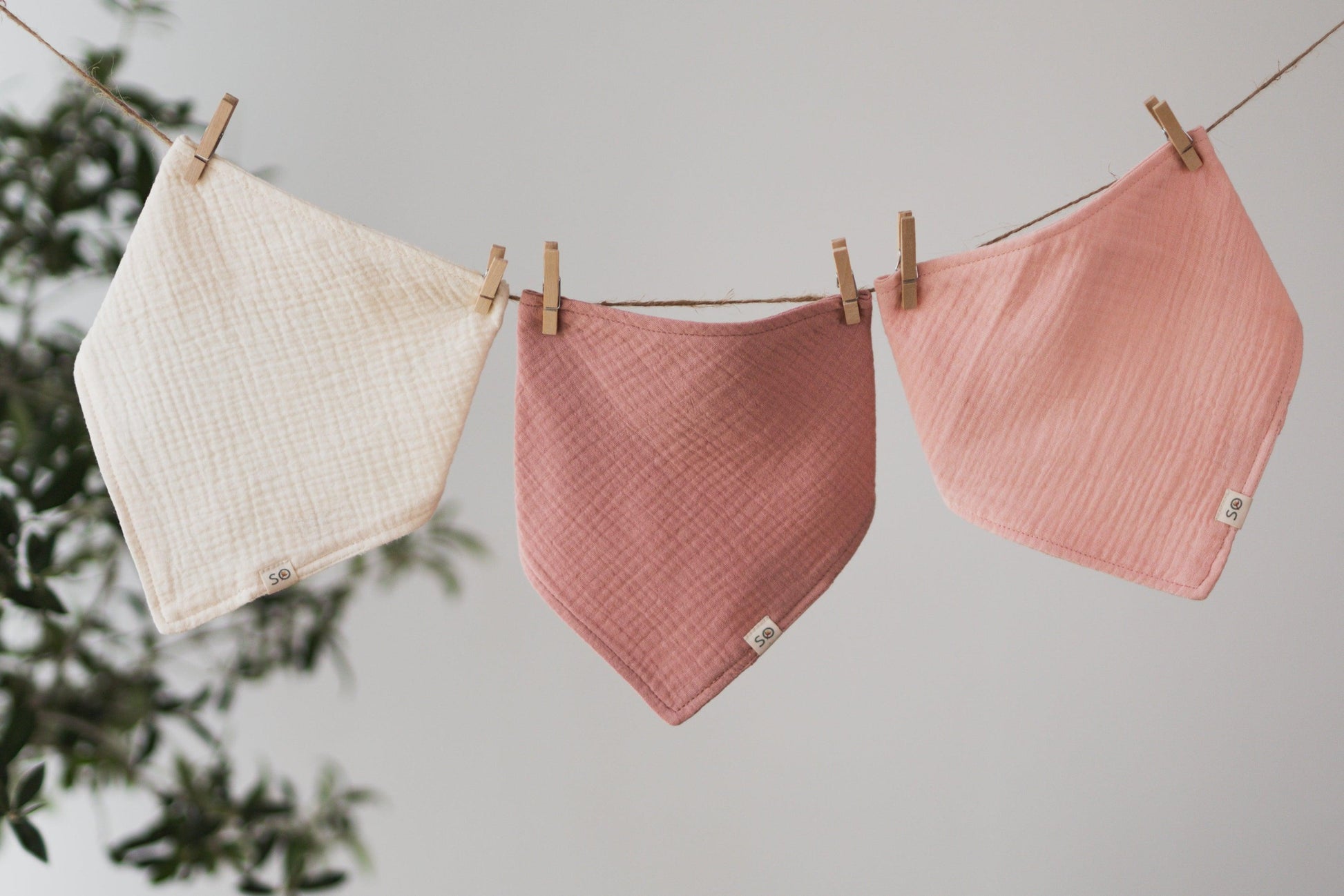 SOALSA baby bibs in cream, dusty rose, and soft pink hanging on a clothesline rutice za dojenčke