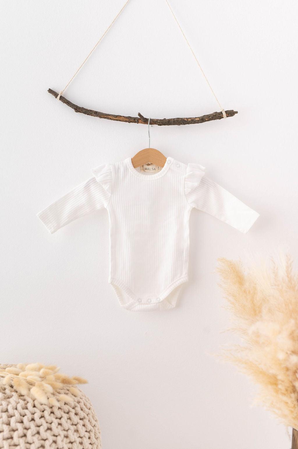 SOALSA beli bombažni otroški bodi za novorojenčka z dolgimi rokavi, obešen na lesen obešalnik.